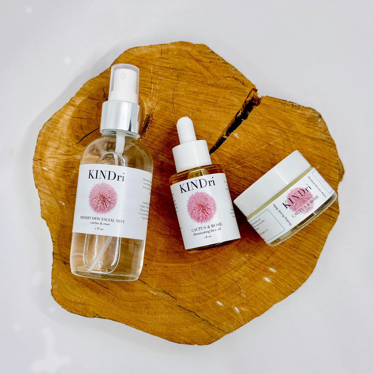 Three KINDri Cactus & Rose skincare products arranged on a wooden slice